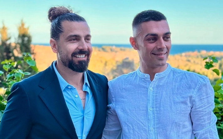 Lolo Drago, Director Terapéutico con barba y pelo recogido, junto a Pau Bertomeu Gilabert, terapeuta con tatuajes en el brazo, ambos sonriendo con profesionalidad frente a un paisaje de colinas y mar en el centro de adicciones Bella Mar de Tarragona.