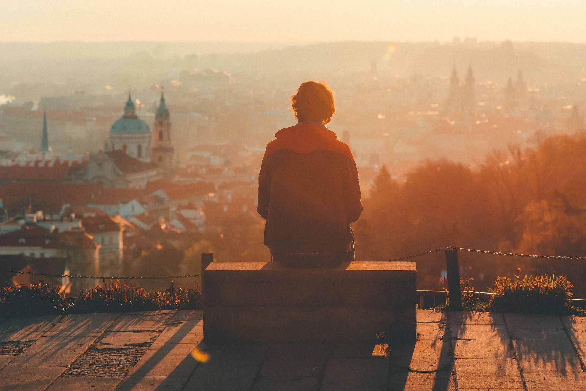 foto del paisaje de una ciudad amaneciendo y delante situado un joven de espaldas viéndolo desde un banco tras superar su adicción al alcohol y viendo su hermosura por primera vez
