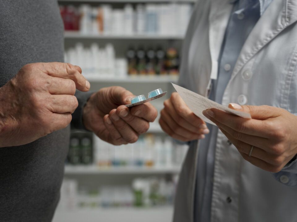Hombre mayor que consulta a una farmacéutica sobre medicamentos