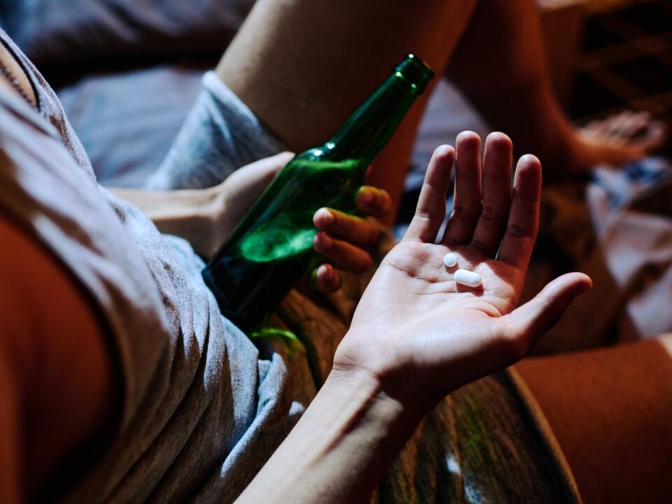 mano sosteniendo u n par de pastillas de drogas de diseño en una fiesta, piensa mezclarlos con cerveza