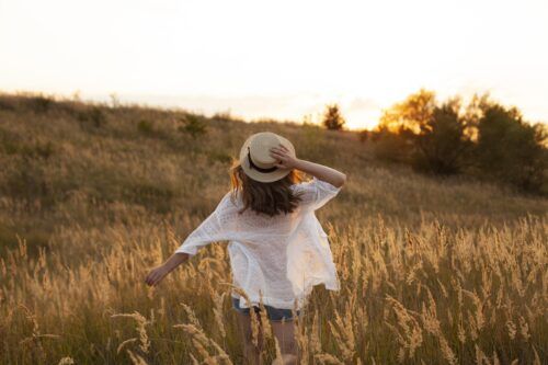 Mujer de espaldas caminando libre por un campo al atardecer, simbolizando la esperanza y la salida de la adicción hacia una vida plena.