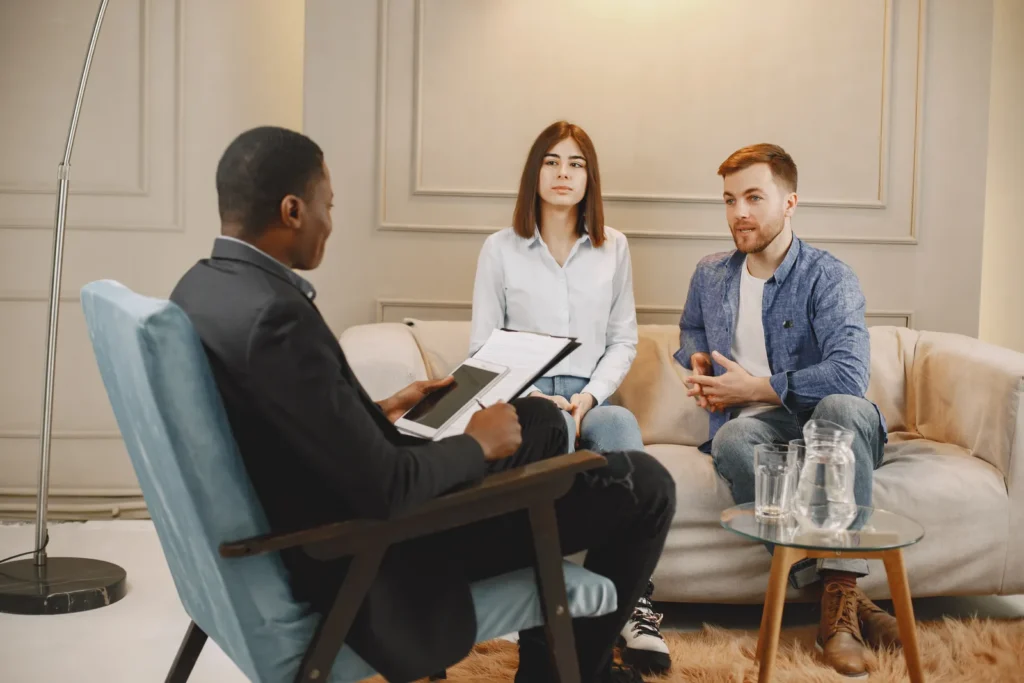 Pareja conversando con un terapeuta durante una sesión.
